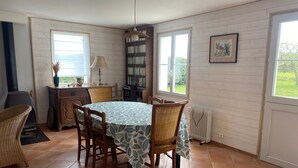 Un comedor acogedor con una mesa redonda, sillas, una estantería y una ventana con vistas a la vegetación.