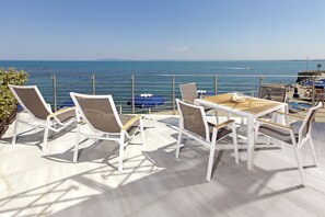 Een terras met een tafel en stoelen, met uitzicht op een waterpartij en verafgelegen land.