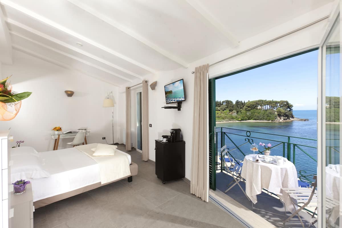 Ein Hotelzimmer mit Bett, Schreibtisch und einem Balkon mit Meerblick.