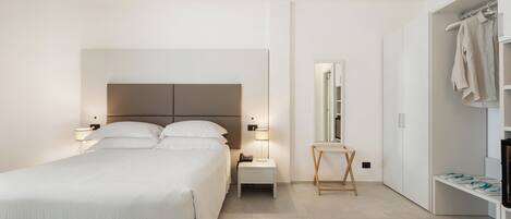 Une chambre d’hôtel moderne avec un grand lit, des tables de chevet, un miroir et une armoire.