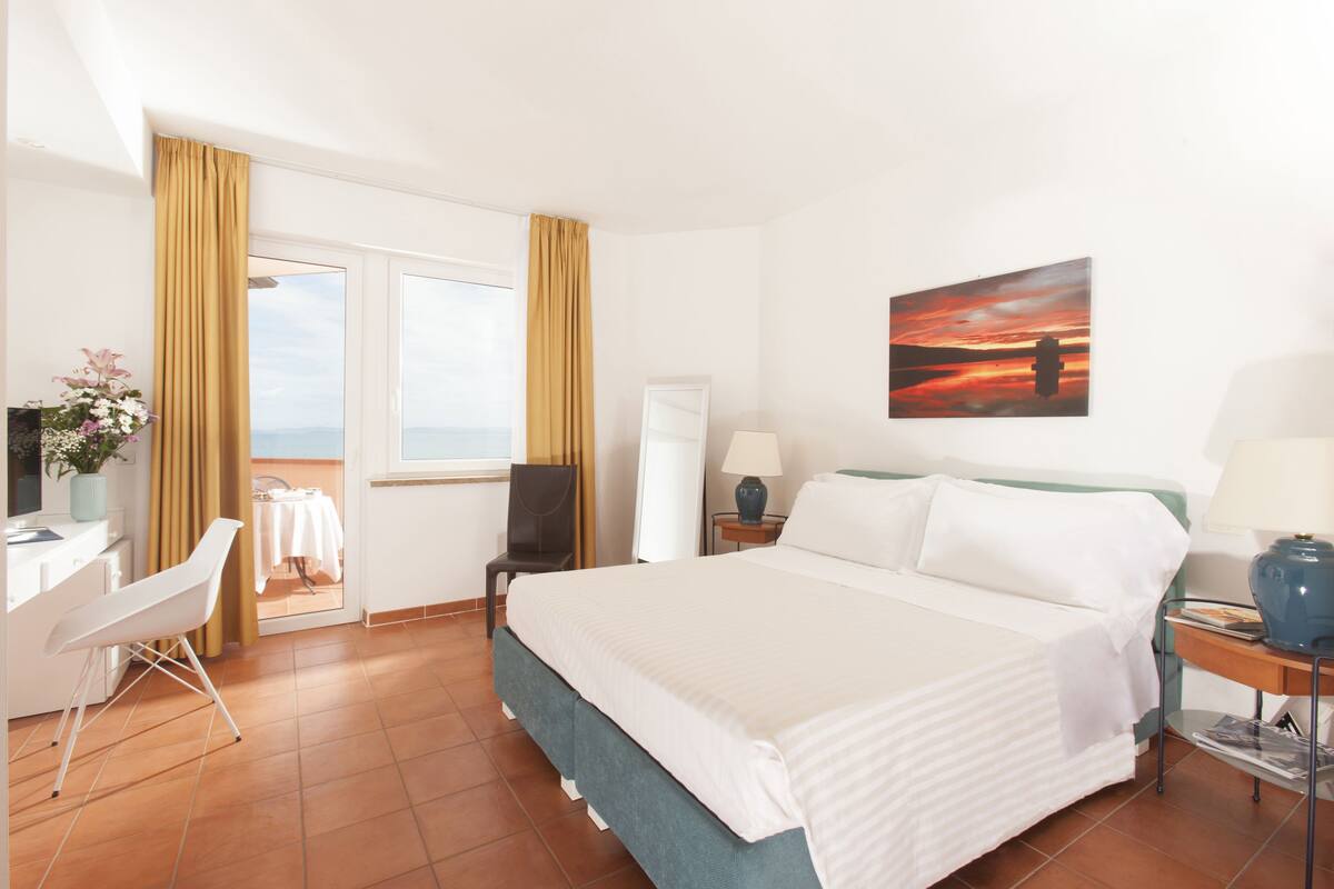 Ein Hotelzimmer mit Bett, Schreibtisch, Stuhl und einem Sonnenuntergangsbild.