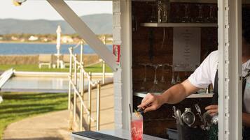 Un stand de vente de bières avec une enseigne, une personne préparant une boisson, et en arrière-plan, une étendue d’eau.