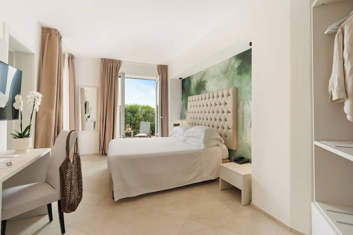 Ein modernes Hotelzimmer mit einem großen Bett, einem Schreibtisch und Blick auf Grünfläche.