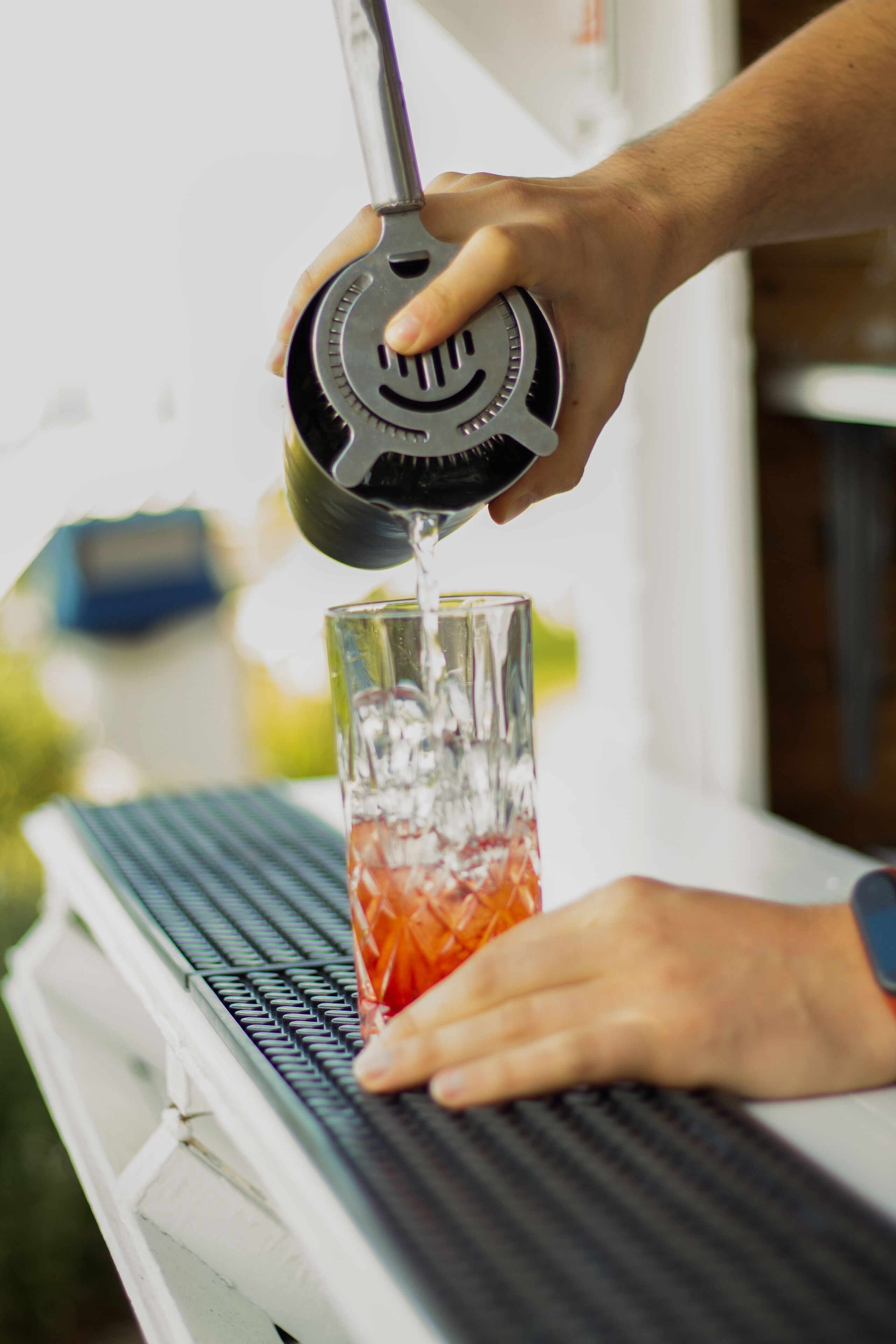Una persona sirve una bebida de una botella en un vaso.