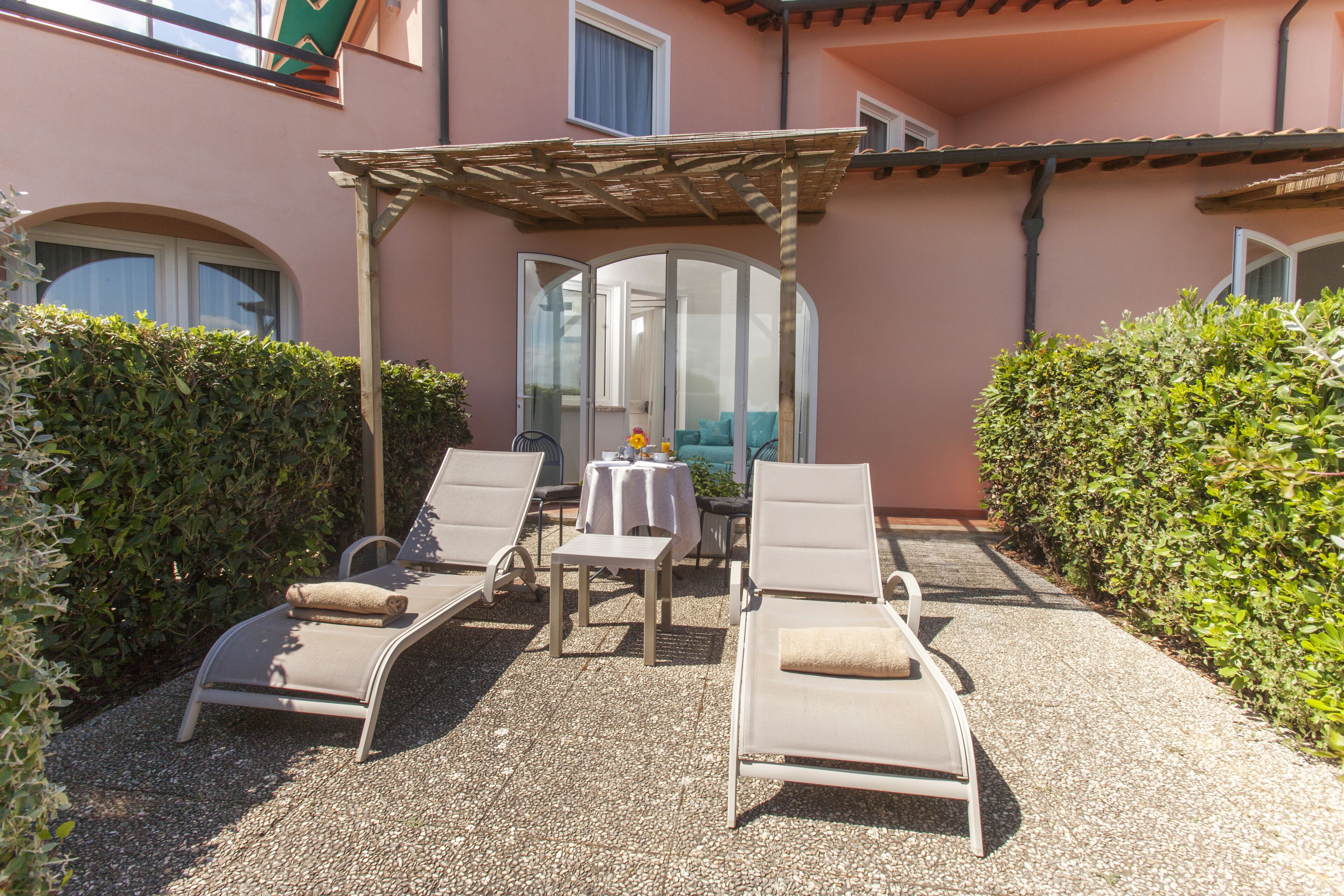 A patio with two lounge chairs, a table, and a pergola.