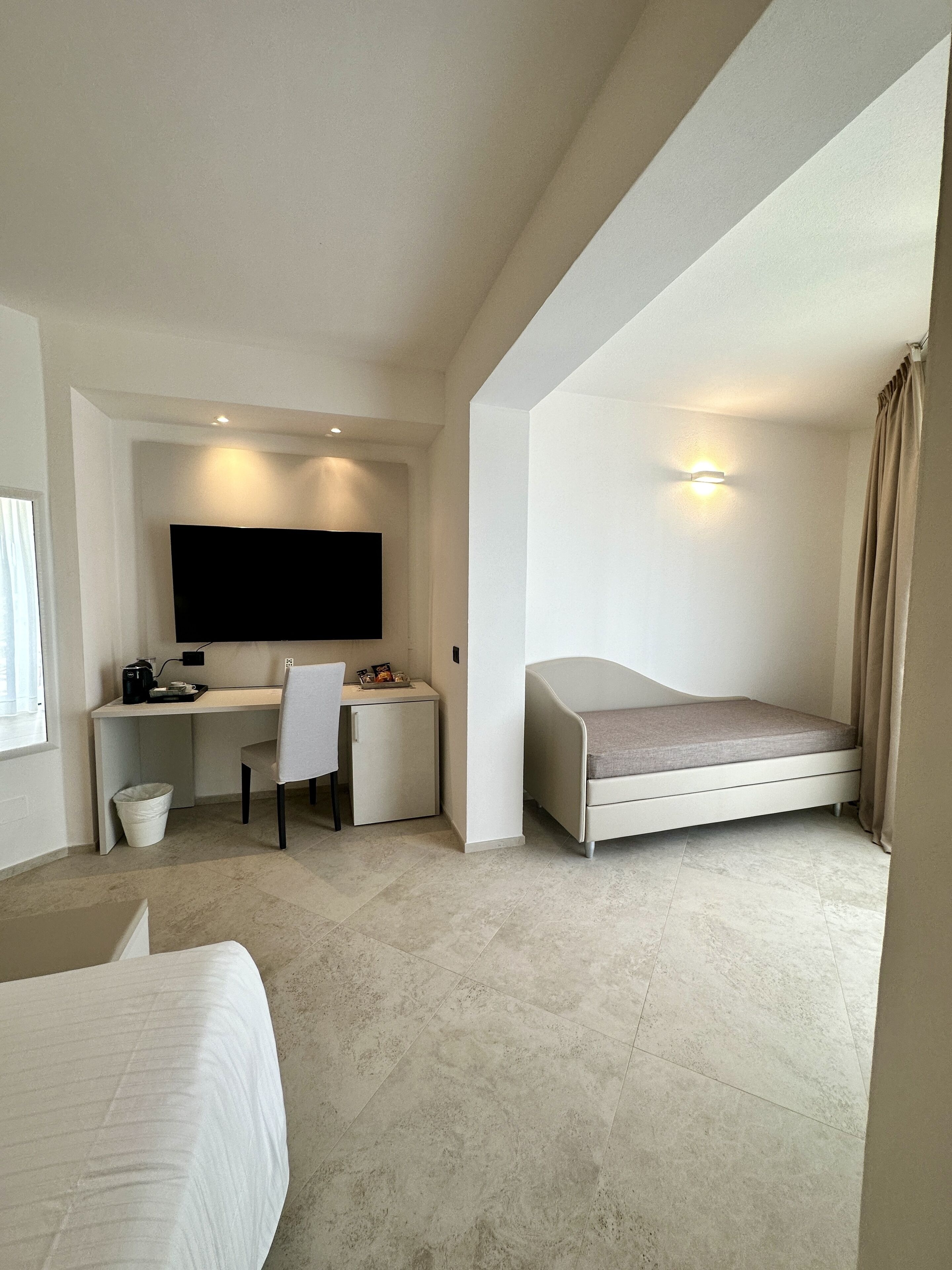 Une chambre d’hôtel moderne équipée d’un lit, d’un bureau, d’une chaise, d’un petit meuble et d’une télévision.