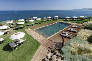 Una piscina al aire libre de temporada, sombrillas, tumbonas