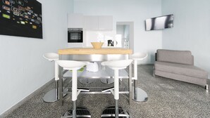 A modern kitchen with a dining table, chairs, a sofa, and a TV. - Primeflats - Apartment Weissensee (Berlin)