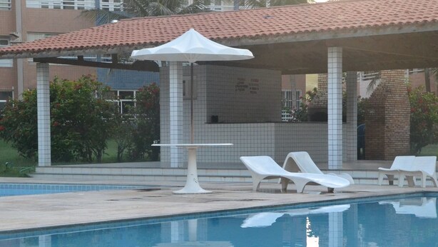 Piscina com espreguiçadeiras e área de estar coberta.