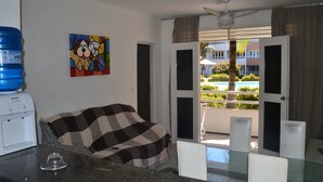 Quarto de hotel com cama, máquina de café, mesa de vidro e varanda com vista para o exterior.