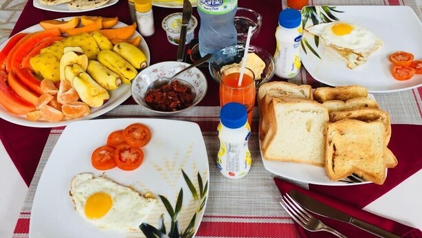 Taula preparada per esmorzar, amb torrades, ous, tomàquets i una varietat de fruites i condiments.