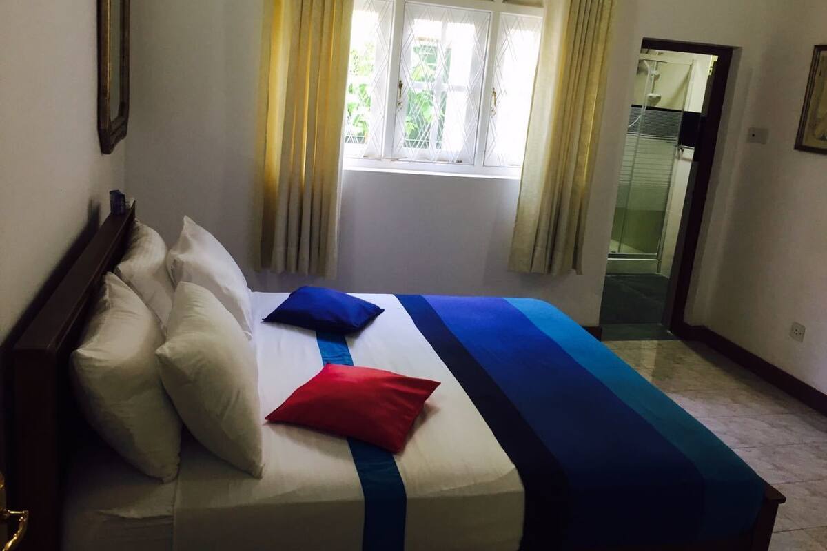 A hotel room with a bed, curtains, a window, and a door.