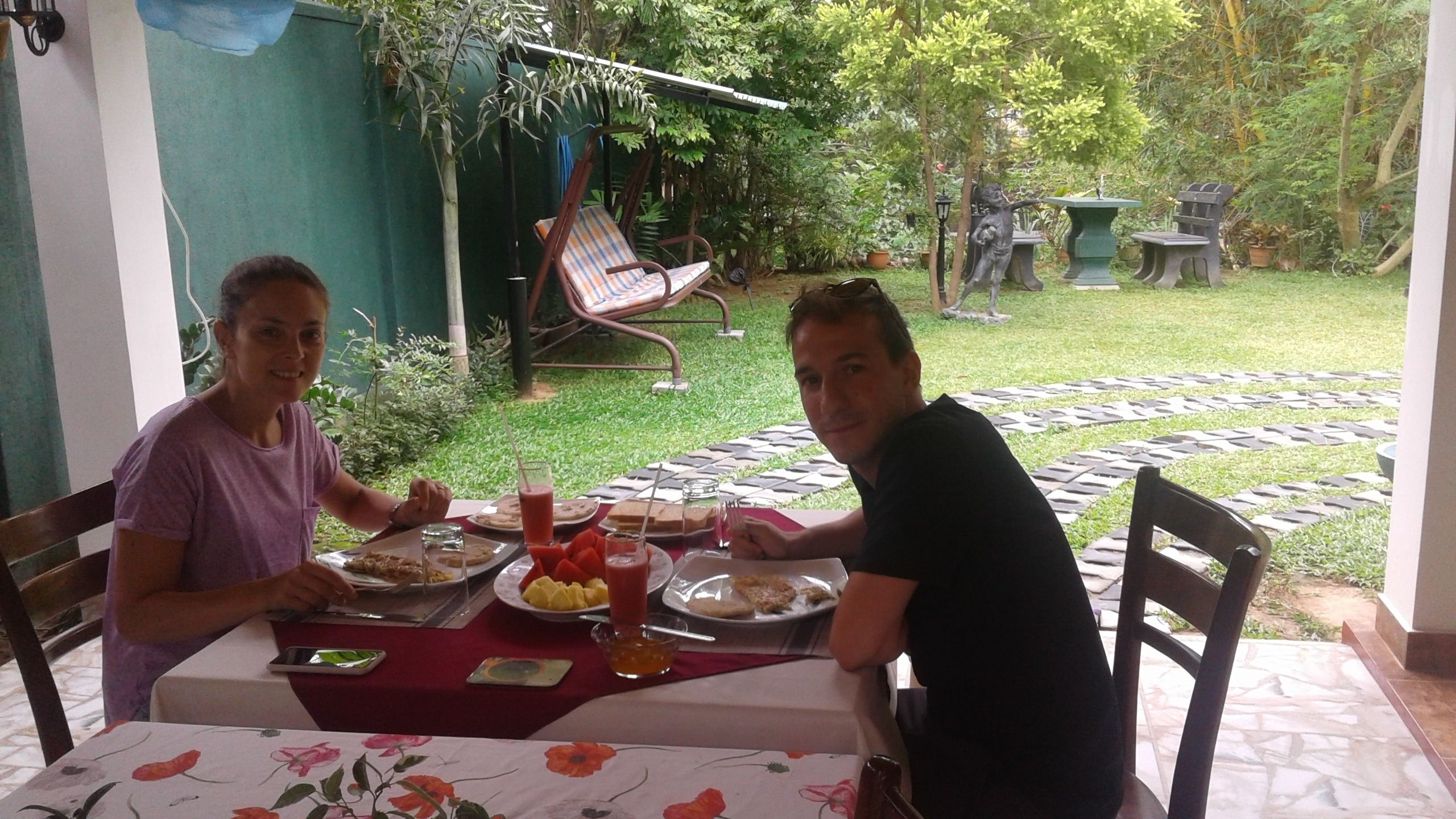 Dos personas cenando en una mesa al aire libre con vista a un jardín.