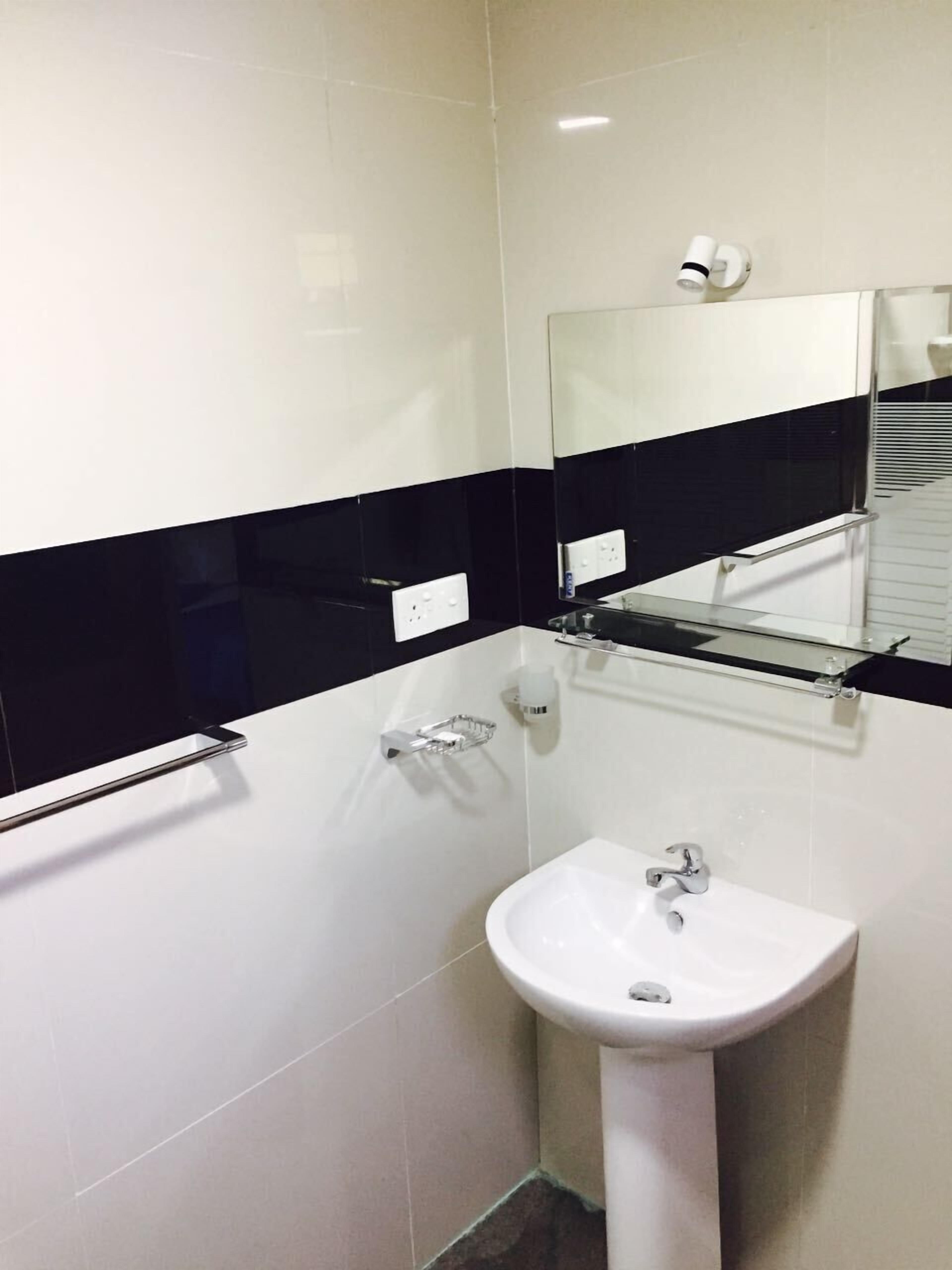A bathroom with a white sink, a mirror, and black-tiled walls.