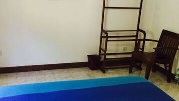 A room with a bed, a chair, a television, and a shelf with a picture frame.