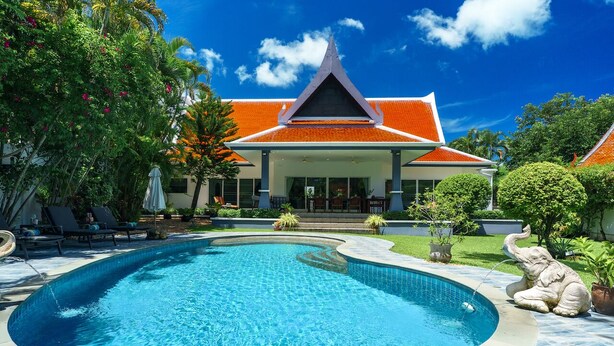 A swimming pool with a curved edge, surrounded by lounge chairs and a statue.
