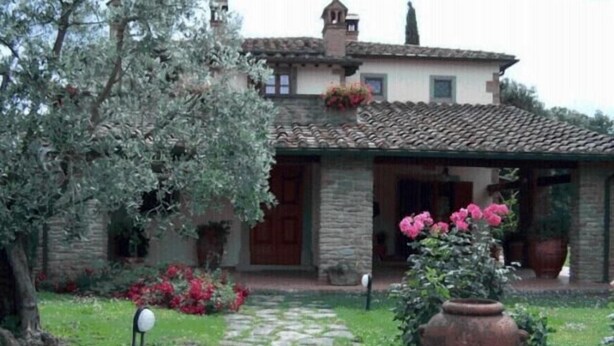 A stone house with a tiled roof, a stone pathway, and potted plants. - B&B Ortali Country House (Arezzo)