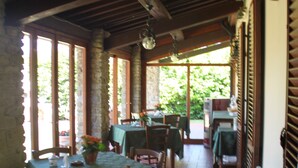 A restaurant with wooden beams and stone walls, featuring tables with green tablecloths and chairs. - B&B Ortali Country House (Arezzo)