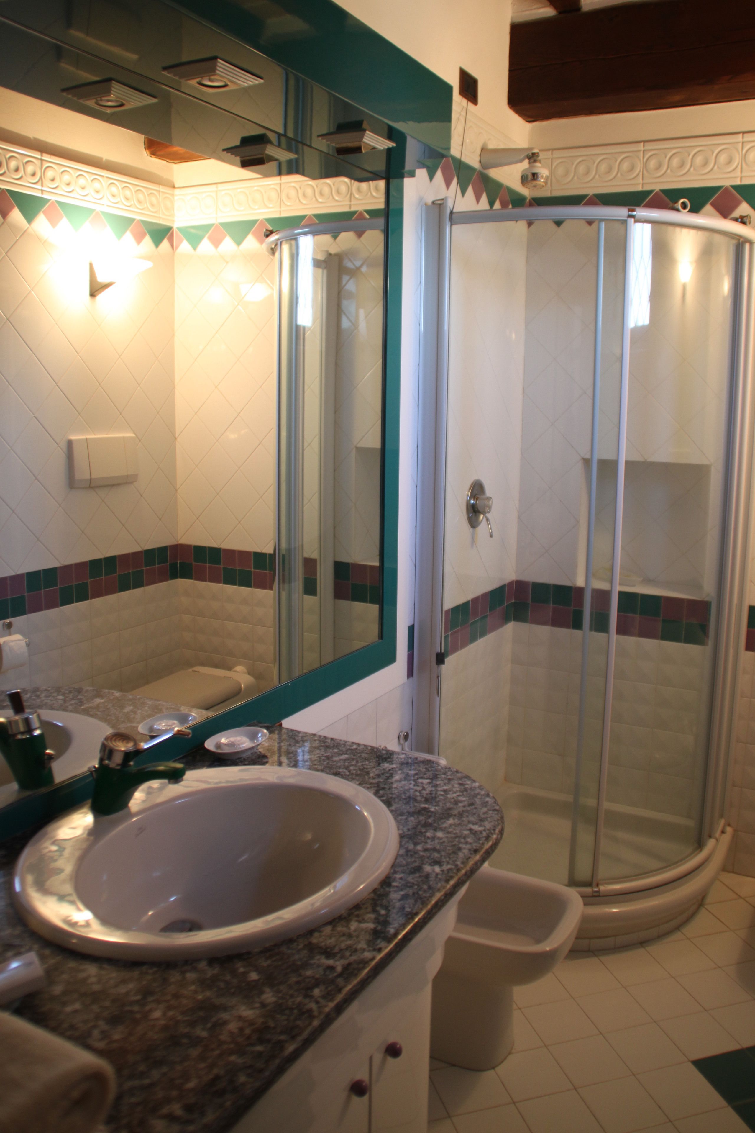 A bathroom with a sink, mirror, shower, and toilet.