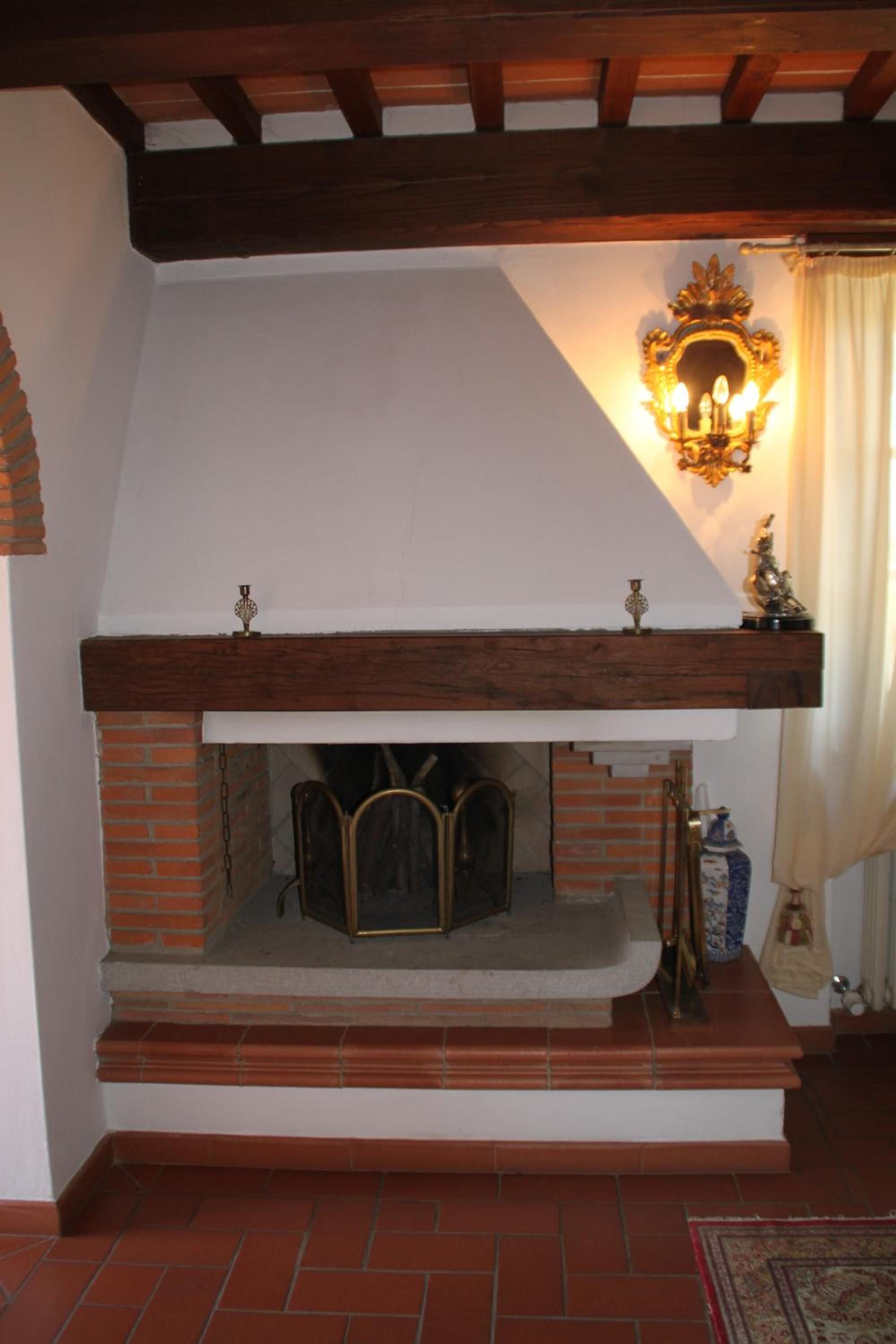 Una chimenea con repisa blanca, revestimiento de ladrillo y una lámpara decorativa encima.