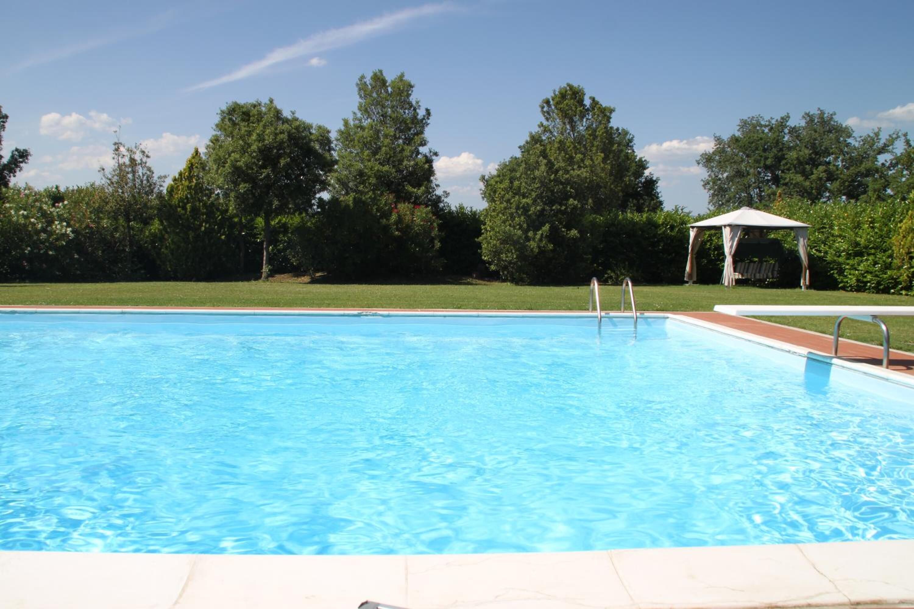 A clear swimming pool with a gazebo in the background.