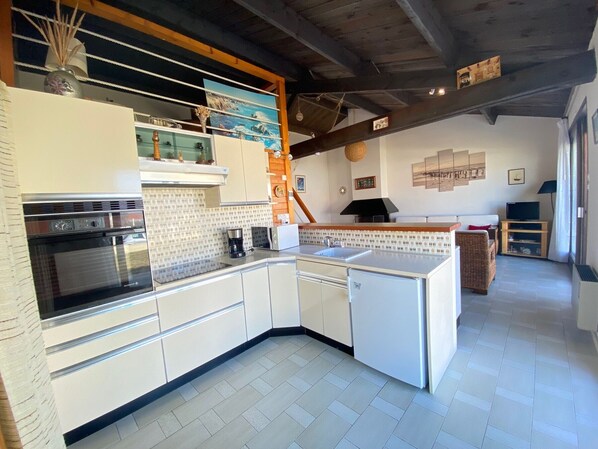 A modern kitchen with white cabinetry, a built-in oven, and a coffee machine.