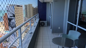 Un balcon avec une balustrade en métal, une table et deux chaises. Un appareil de climatisation portant l’inscription « ELGIN » est fixé au mur.