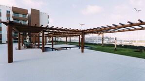 Un espace extérieur aménagé en terrasse, avec une pergola en bois, des sièges et une piscine.