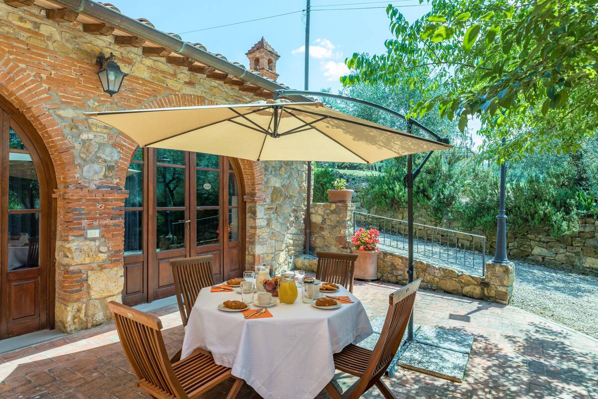 A patio with a round table, chairs, and a large umbrella.