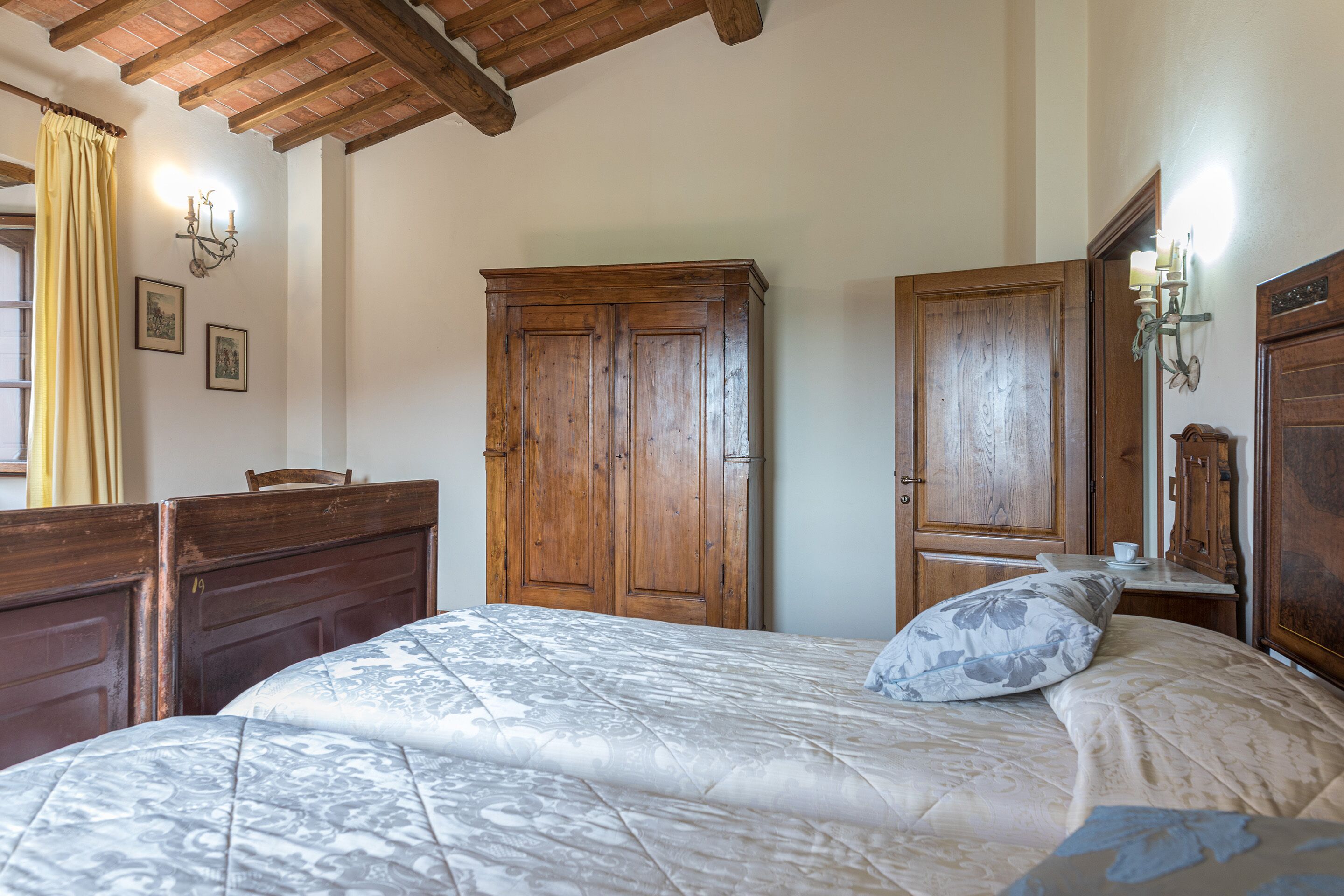 A bedroom with a large bed, wooden wardrobe, and a wooden ceiling.