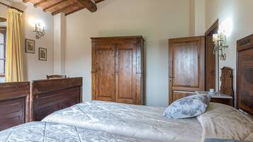 A bedroom with a large bed, wooden wardrobe, and a wooden ceiling.