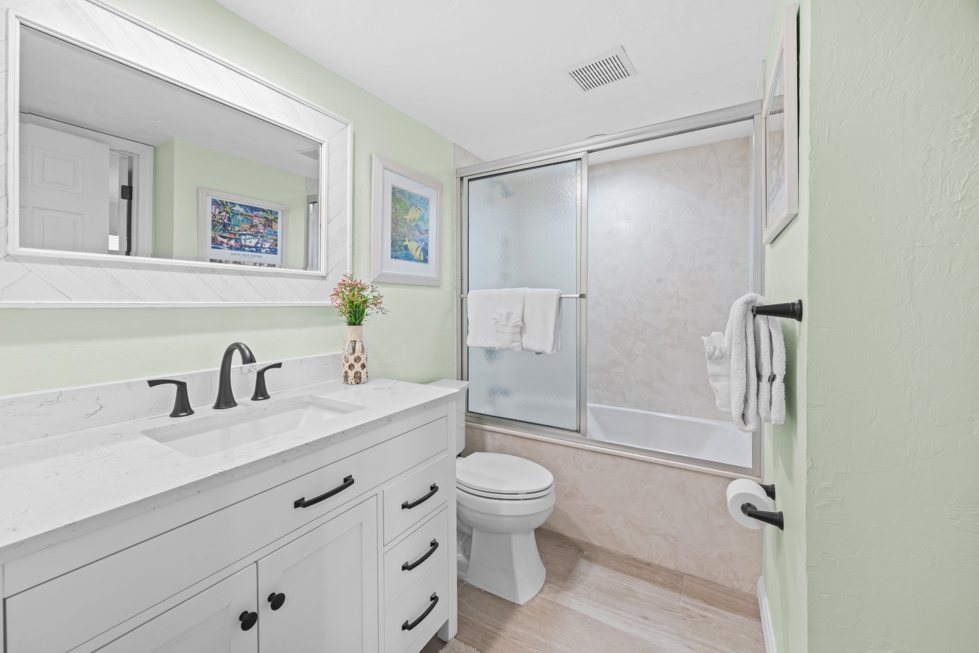A bathroom with a white sink, a toilet, and a glass-enclosed shower.