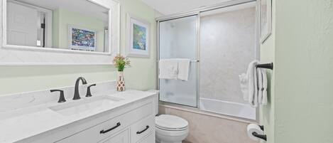 A bathroom with a white sink, a toilet, and a glass-enclosed shower.