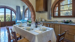 A dining area with a table set for four, a brick archway, wooden cabinets, and a view of the outdoors.