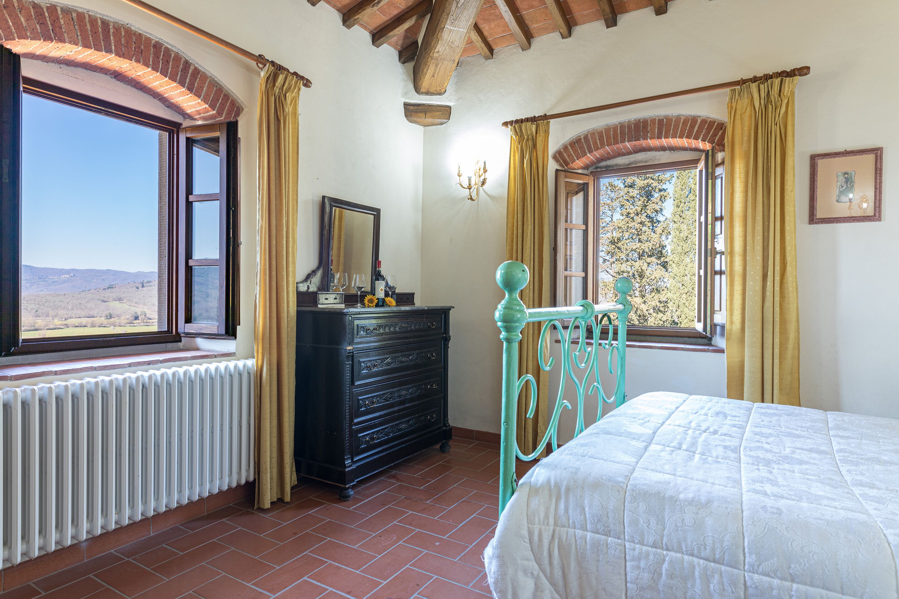 Ein Schlafzimmer mit Bett, Schminktisch und Fenstern mit Vorhängen.