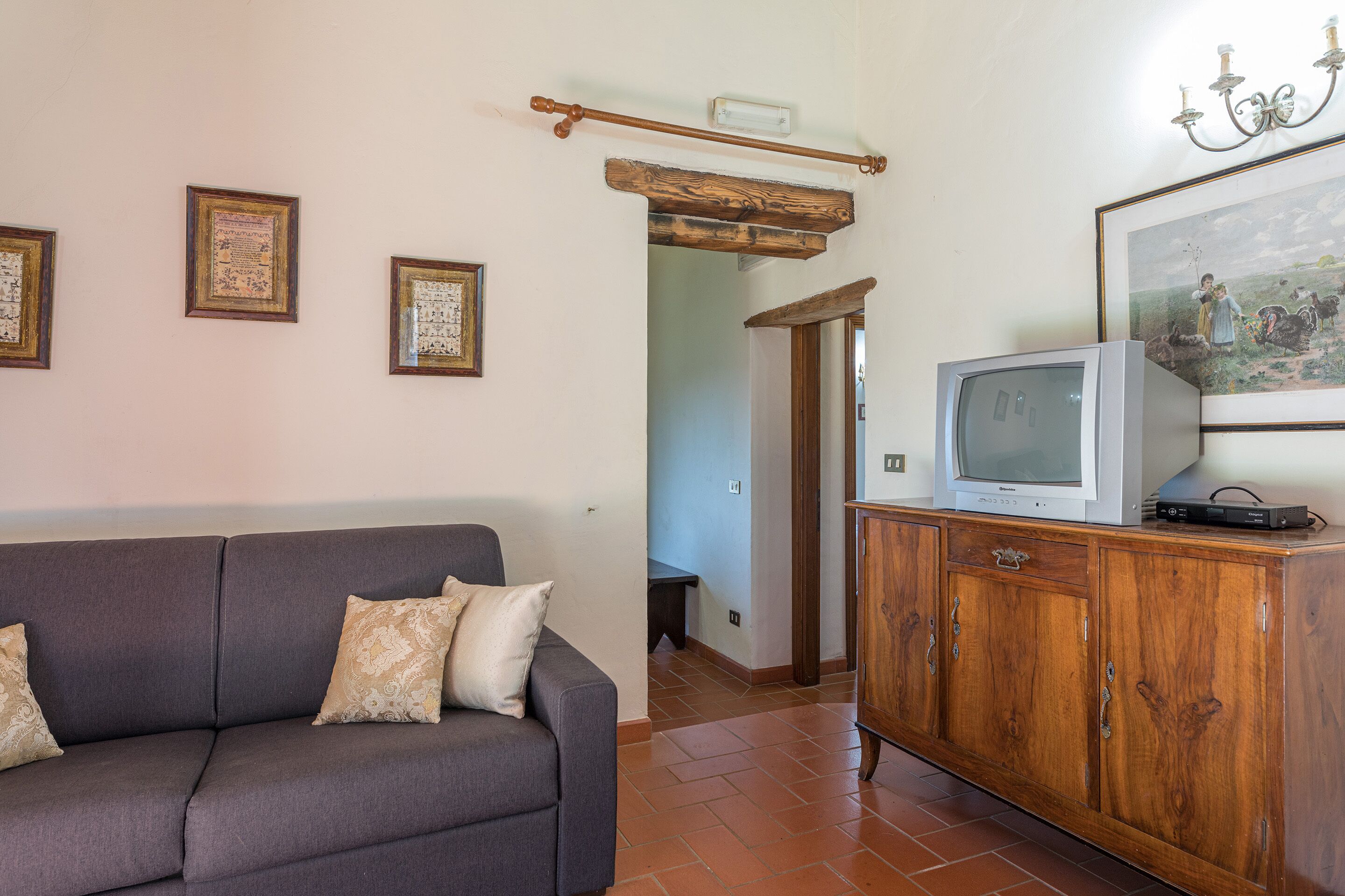 Una sala de estar con un sofá gris, un mueble de madera y cuadros enmarcados en la pared.