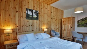 A wooden-paneled bedroom with a bed, bedside tables, and a chair. - Rezort Gothal Apartmány a Penzióny (Liptovská Osada)
