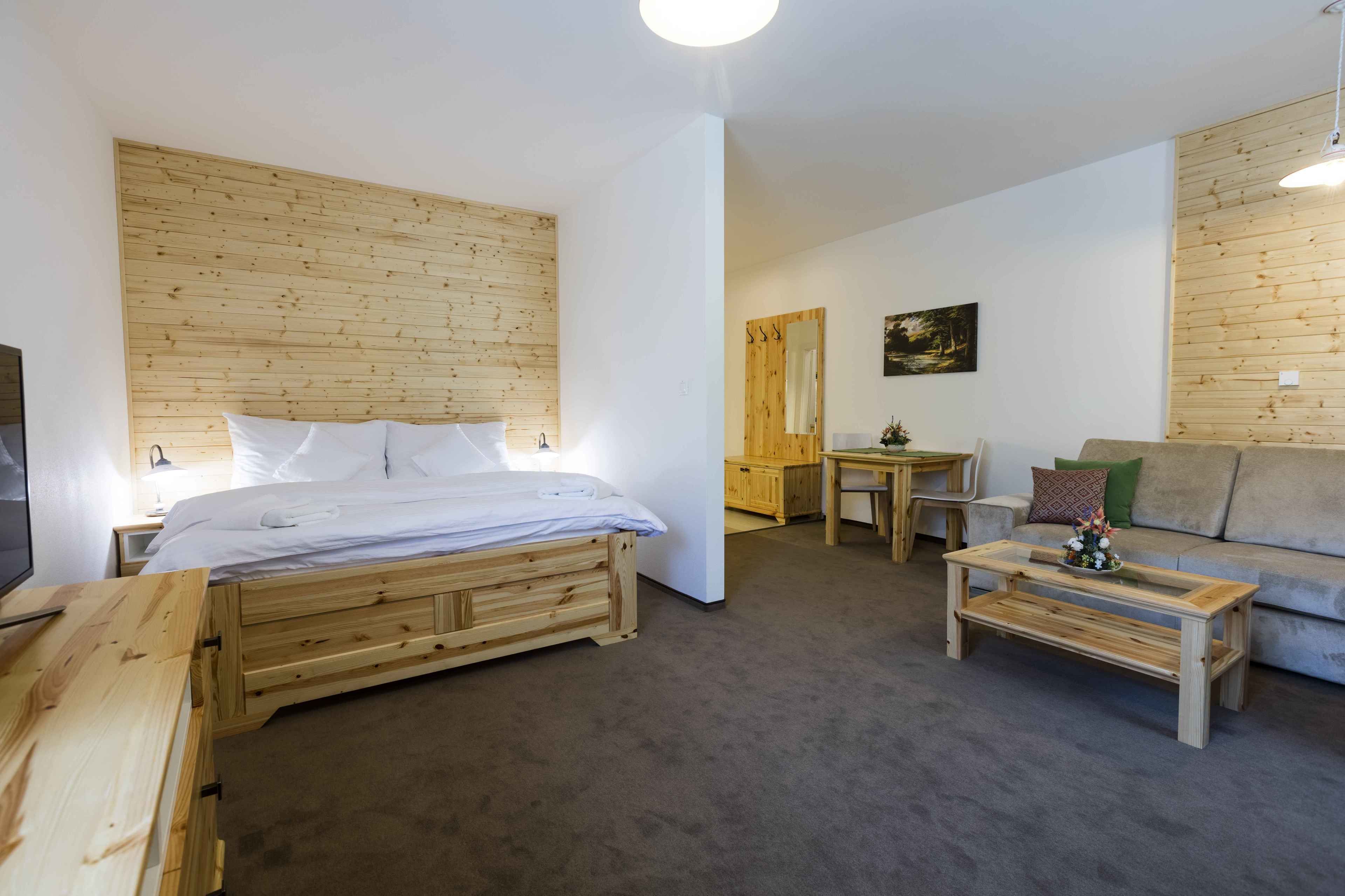 Un dormitorio con cama, mesita de noche, escritorio, mesa de centro y sofá de madera.