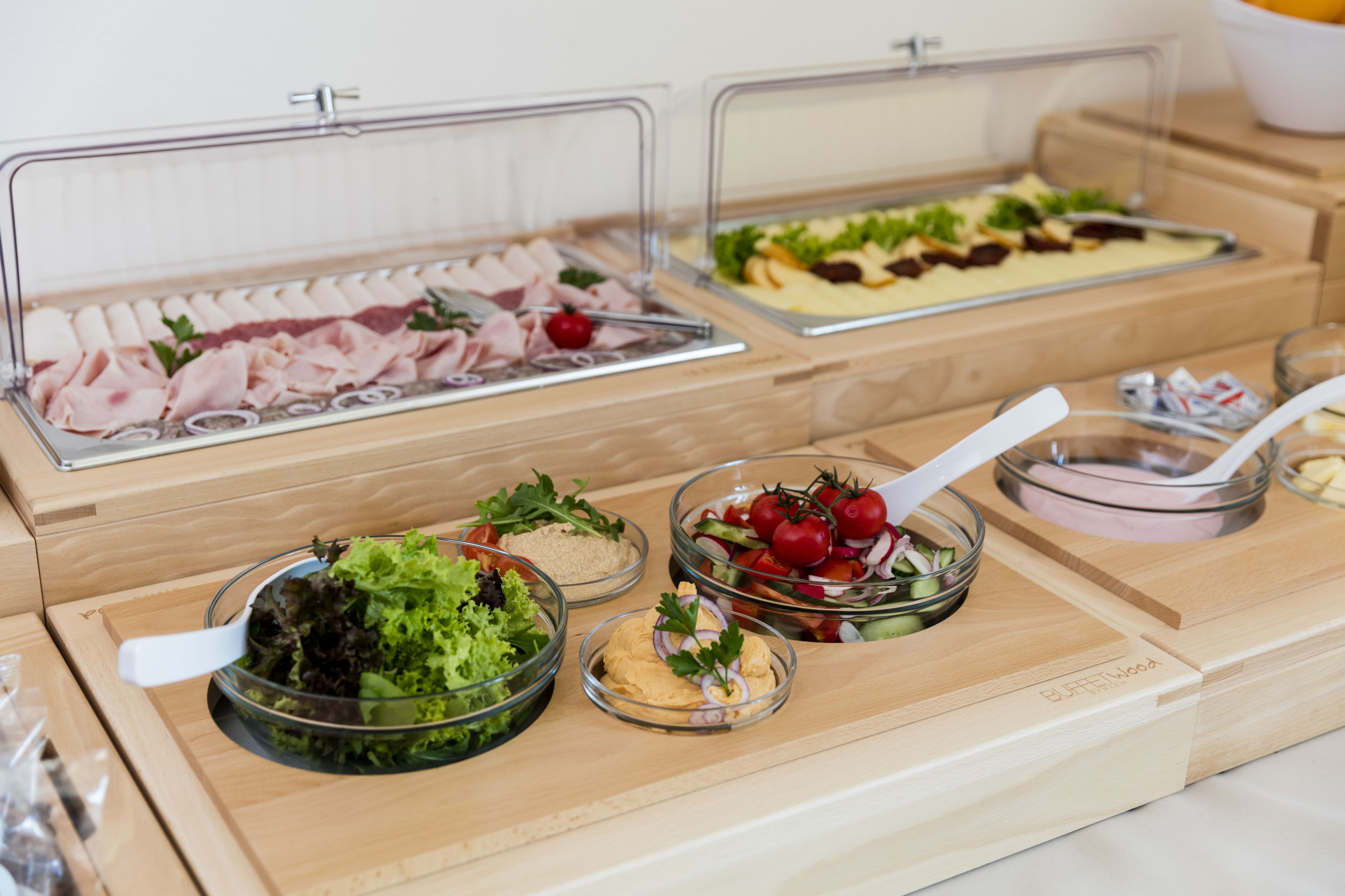 Buffet com diversas opções de comida, incluindo saladas, carnes e patês.
