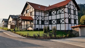 A traditional half-timbered building with a red-tiled roof, a stone foundation, and a well-maintained lawn. - Rezort Gothal Apartmány a Penzióny (Liptovská Osada)