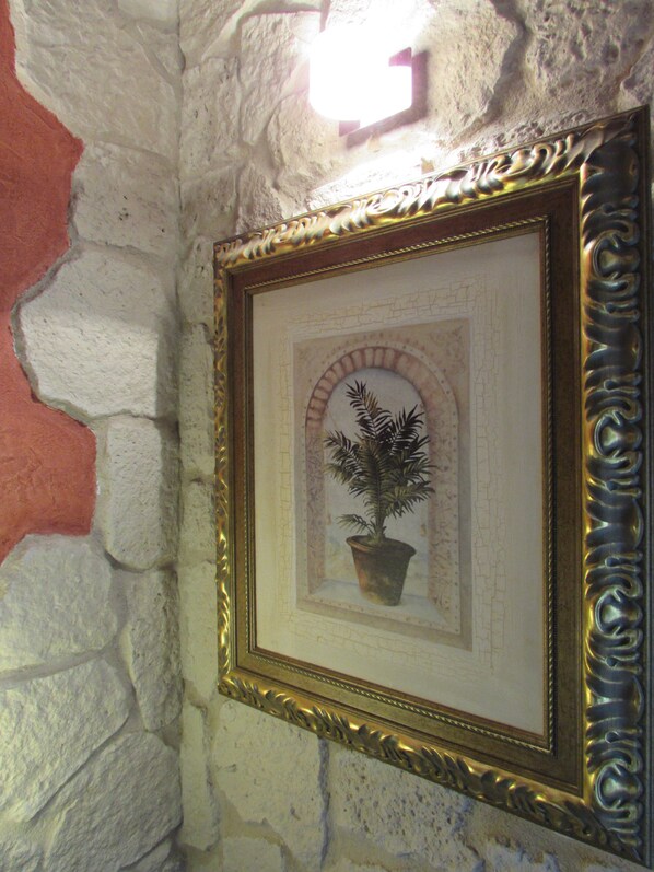 Une photo encadrée représentant une plante en pot, accrochée à un mur texturé.