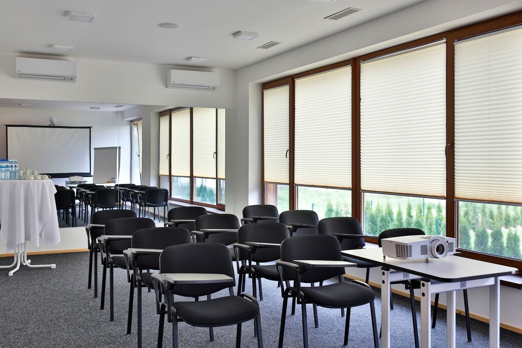 A conference room with rows of chairs, a projector, and a table with water bottles.