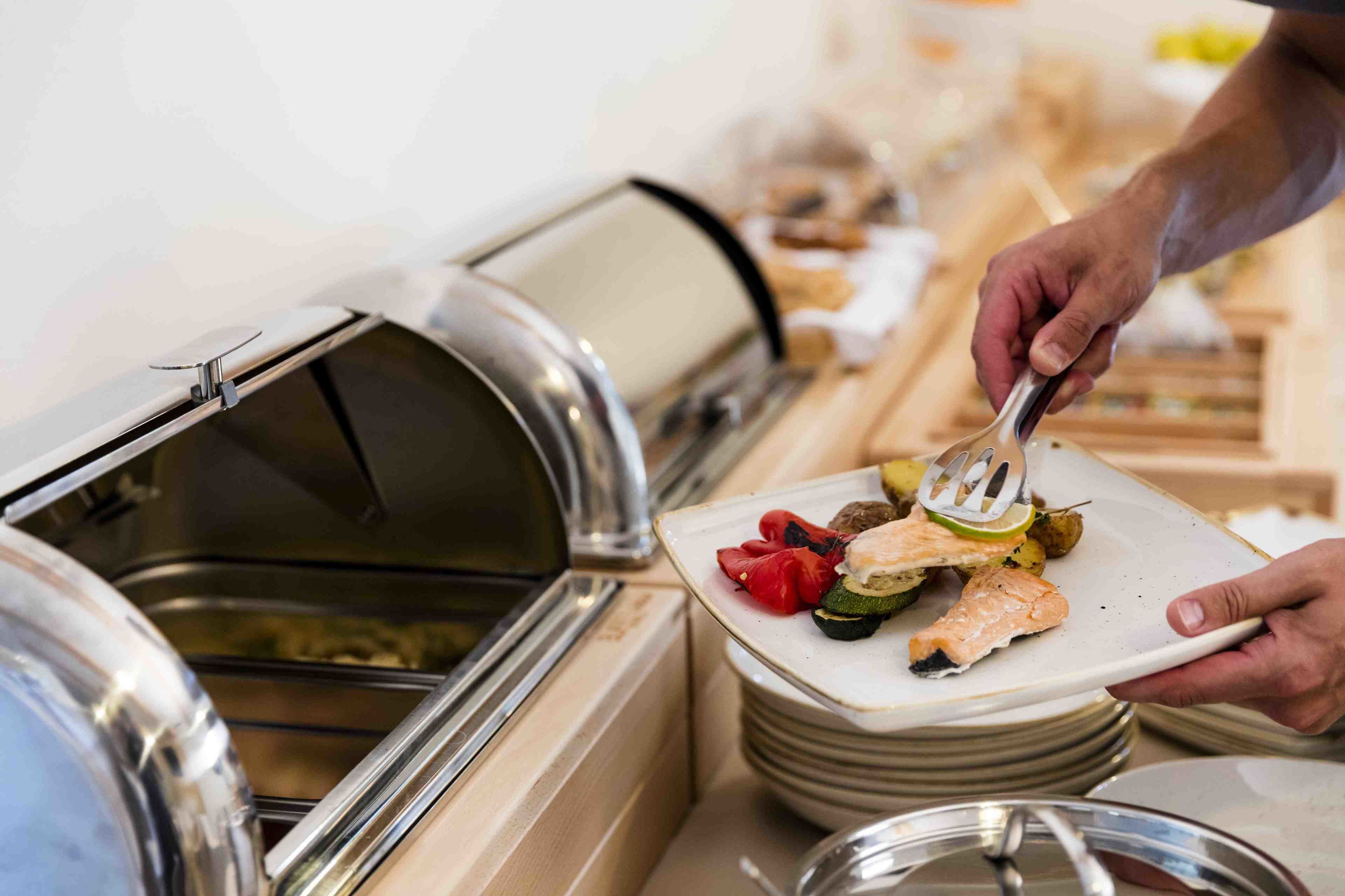 Montaje de bufé con una variedad de alimentos, incluyendo salmón y verduras.