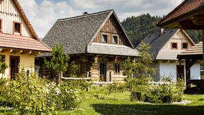 Una casa de madera tradicional con techo inclinado, rodeada de un jardín bien cuidado con diversas plantas y flores.