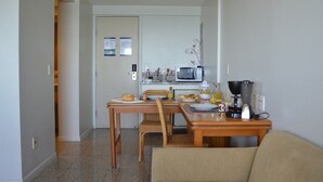 A compact living space with a kitchenette, a dining area with a table and chairs, and a sofa. - OP Flat Vip Frente Mar (Fortaleza)