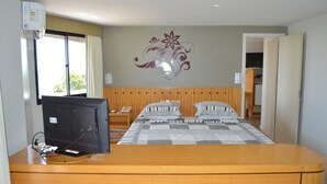 A hotel room with a bed, a television on a wooden table, a decorative wall piece, and a window with curtains. - OP Flat Vip Frente Mar (Fortaleza)