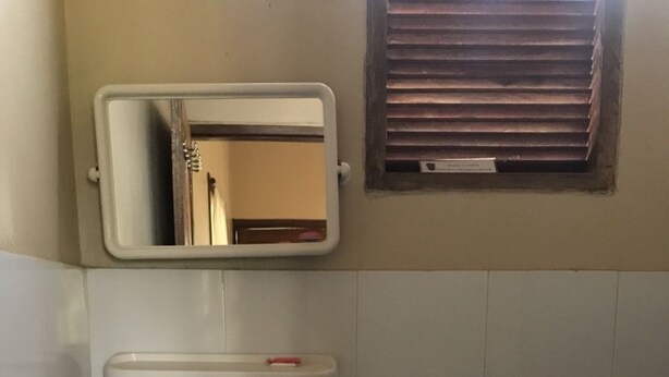 A bathroom with a sink, mirror, toilet, and a trash bin. - Sweet Home Resort at Pai (Pai)
