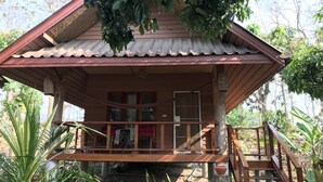A wooden cabin with a porch, a staircase, and a view of the surrounding vegetation. - Sweet Home Resort at Pai (Pai)