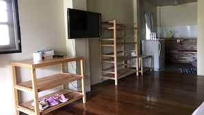 A room with wooden flooring, a television mounted on the wall, and a kitchen area with a refrigerator and cabinets. - Sweet Home Resort at Pai (Pai)