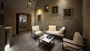 A room with a stone wall, a wooden door, a sofa, a coffee table, and a chair. - Hotel Piru Wasi Arequipa (Arequipa)